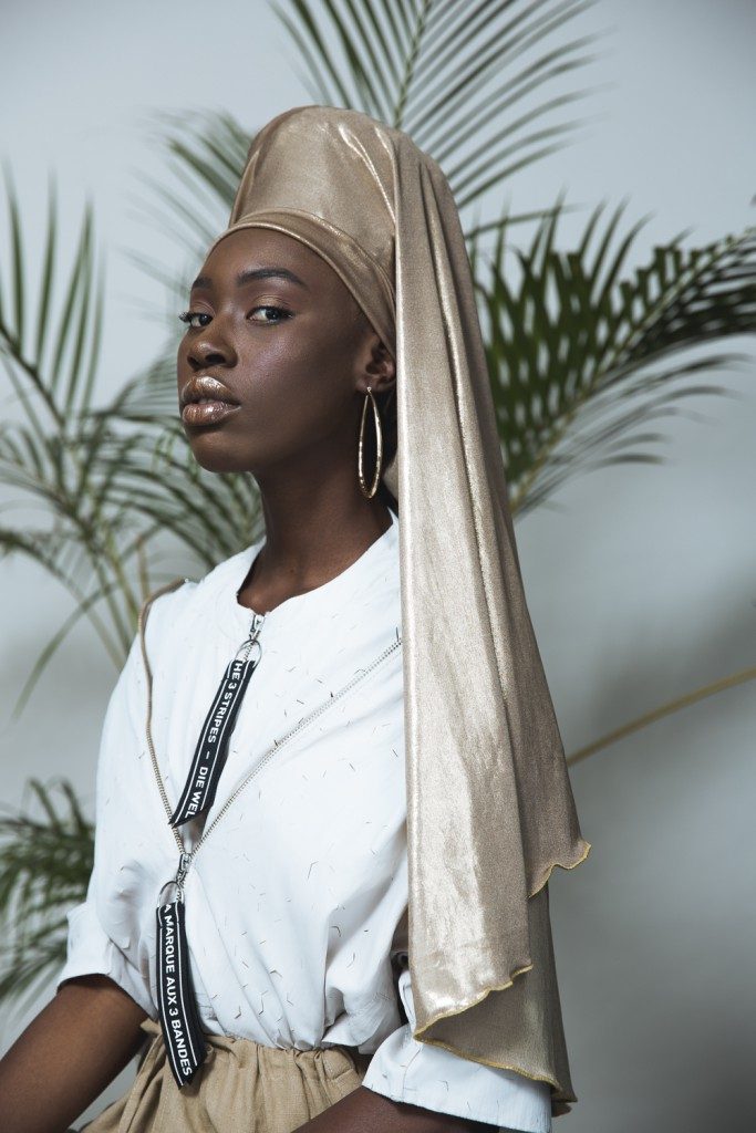 Tatenda WekwaTenzi standing regally in a white dress with tan silk headwrap